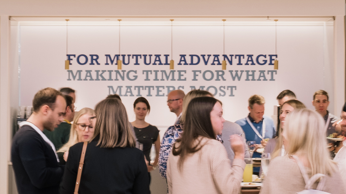 Employees socializing by a "for mutual advantage" sign at a Liberty Specialty Markets event